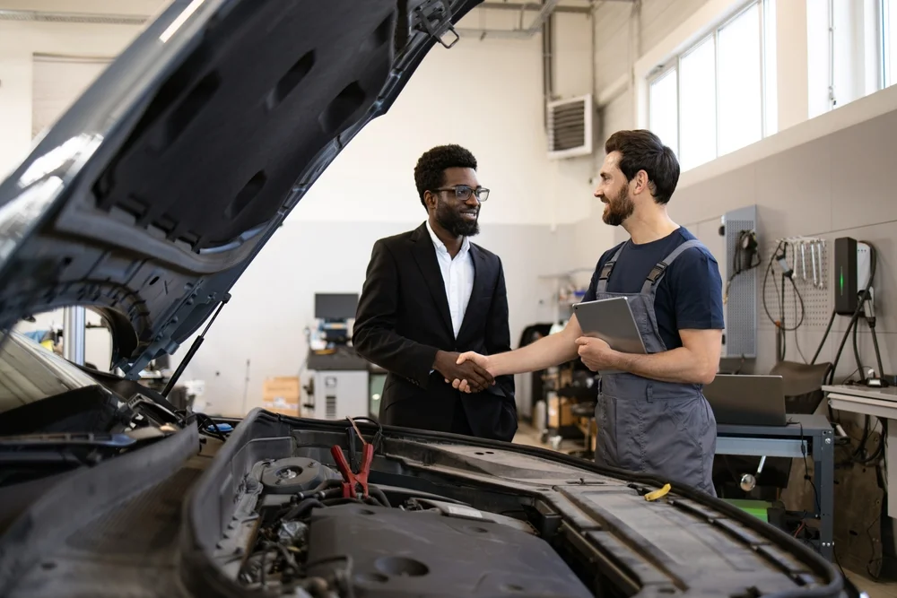 Mechanic in uniform shaking hands with satisfied customer