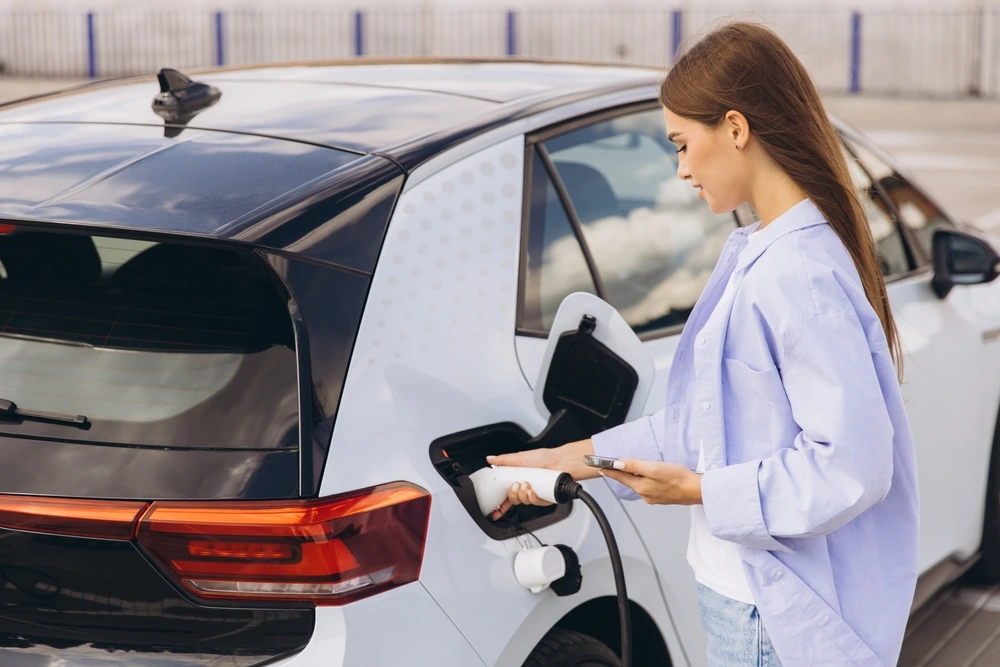 young cute lady charging her electric car
